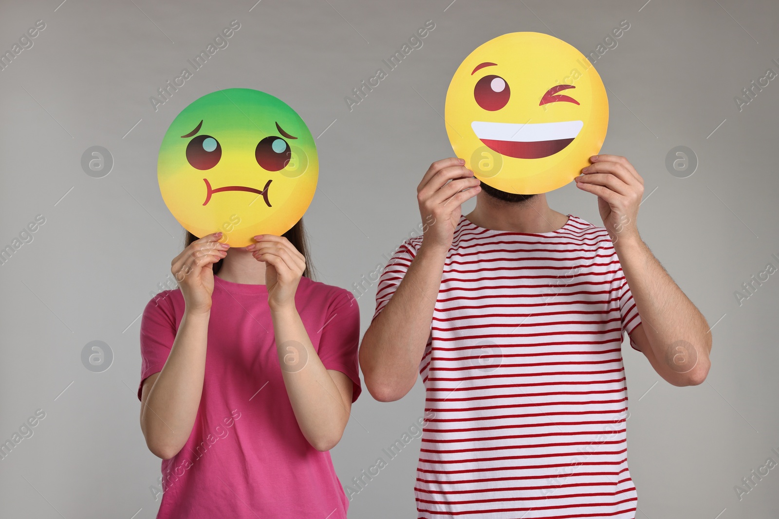 Photo of People covering faces with emoticons on grey background