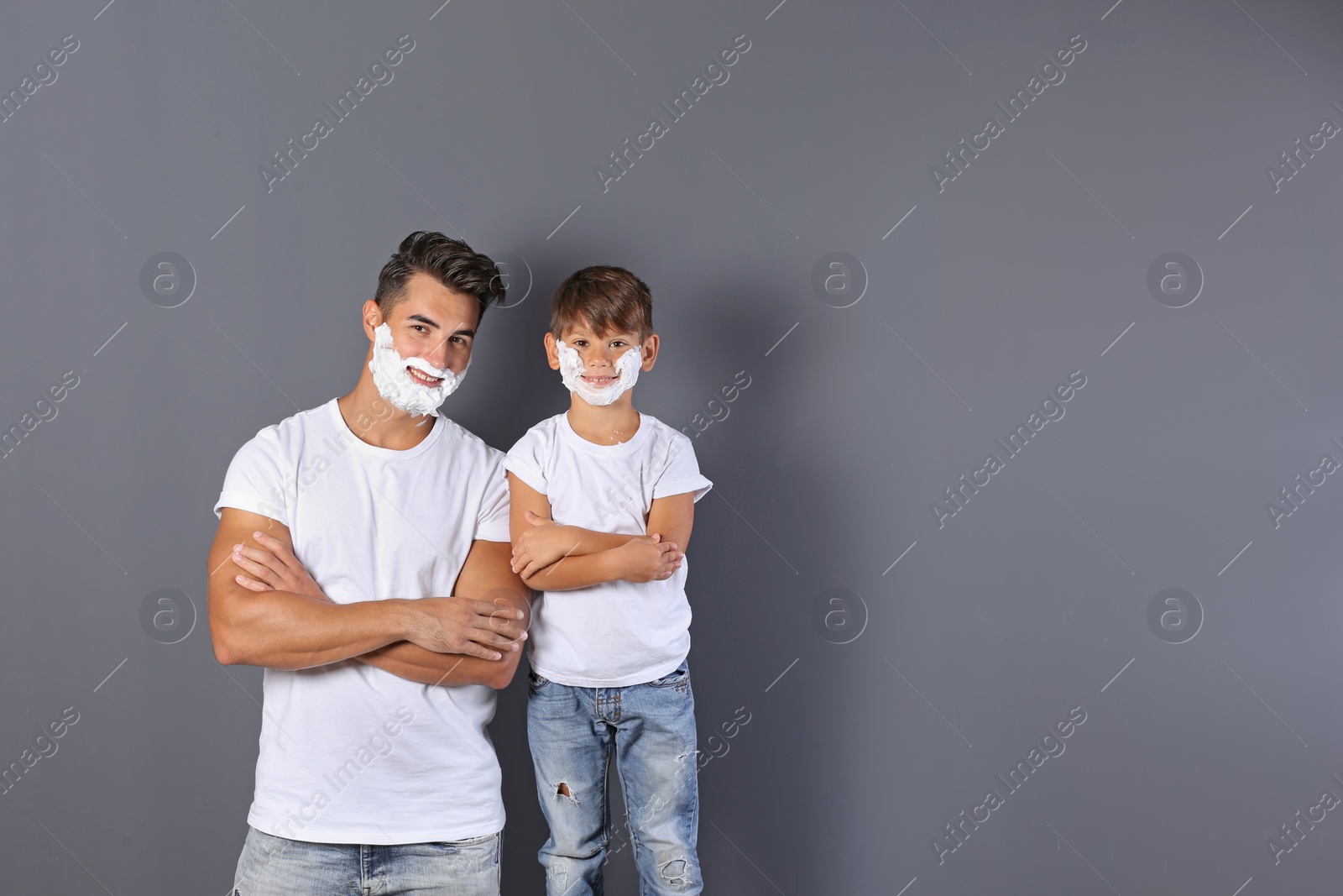 Photo of Father and son with shaving foam on faces against color background. Space for text