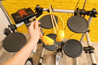 Woman with headphones near modern electronic drum kit indoors, closeup. Musical instrument