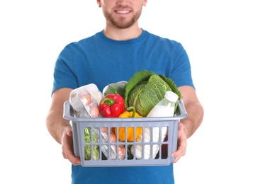 Photo of Delivery man holding plastic crate with food products on white background, closeup