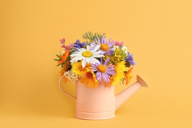 Photo of Pink watering can with beautiful flowers on yellow background