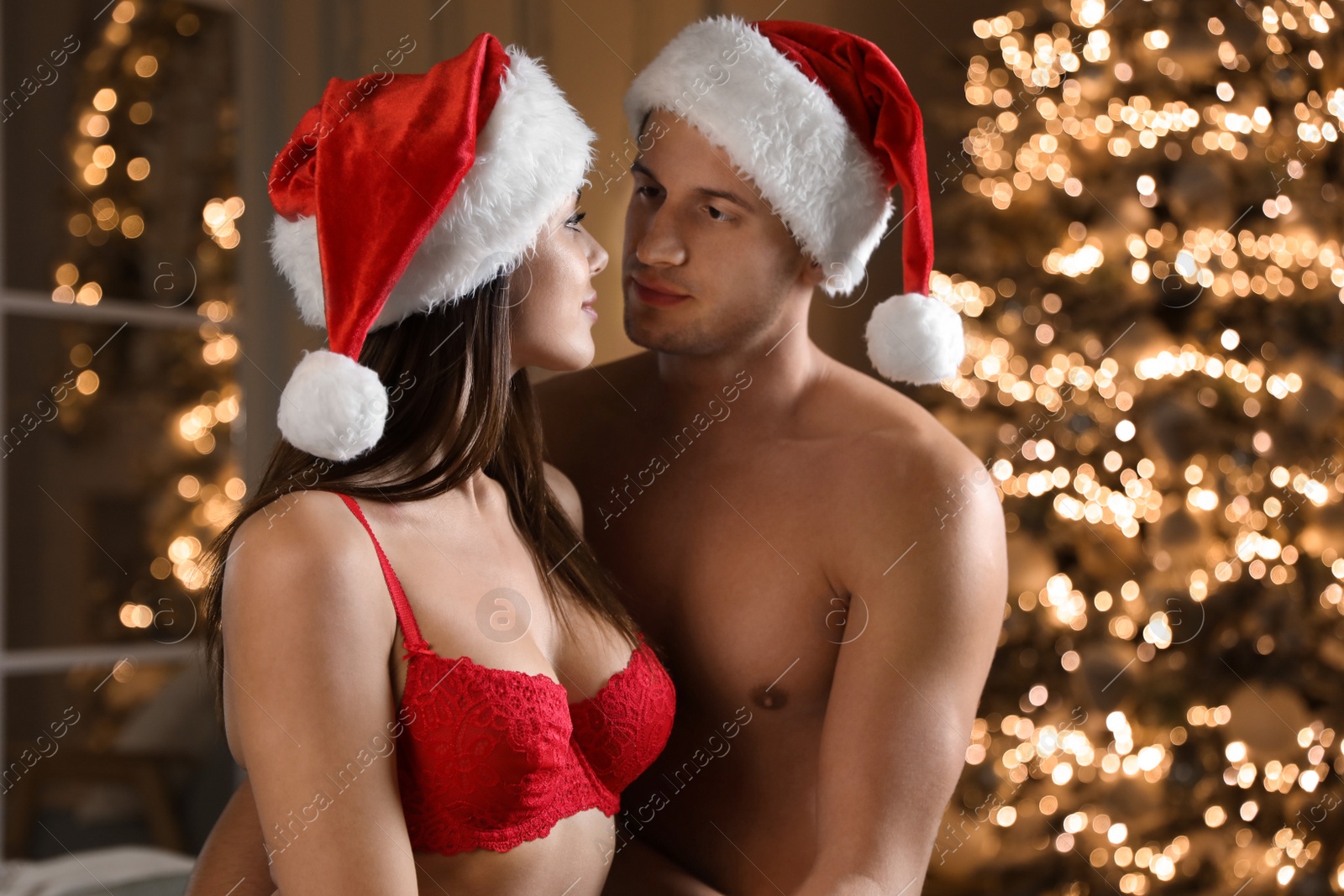 Photo of Passionate young couple enjoying each other in room decorated for Christmas