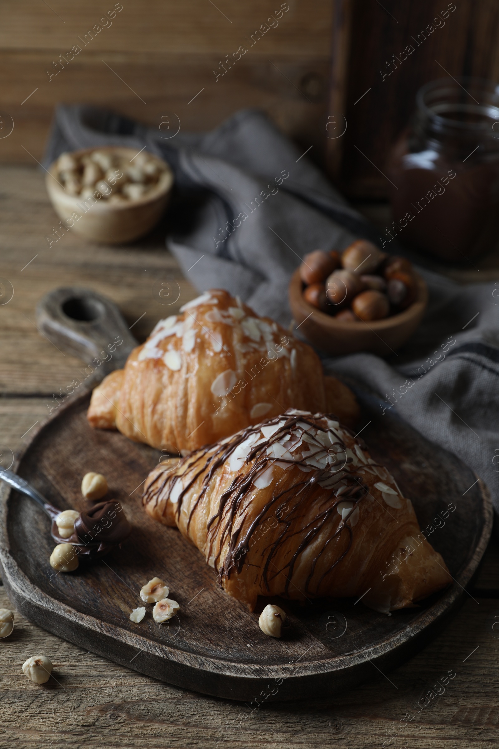 Photo of Delicious croissants with chocolate and nuts on wooden table