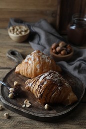 Photo of Delicious croissants with chocolate and nuts on wooden table