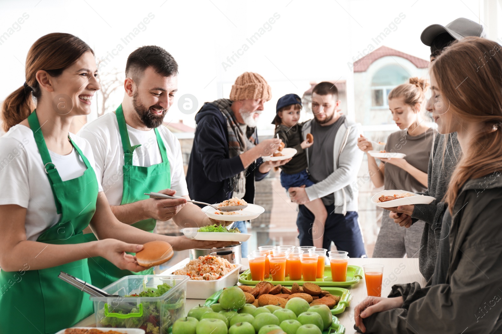 Photo of Volunteers giving food to poor people indoors