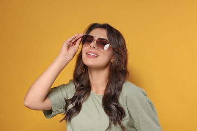Photo of Happy beautiful woman with stylish sunglasses on orange background