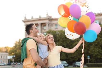 Photo of Happy family with colorful balloons outdoors on sunny day