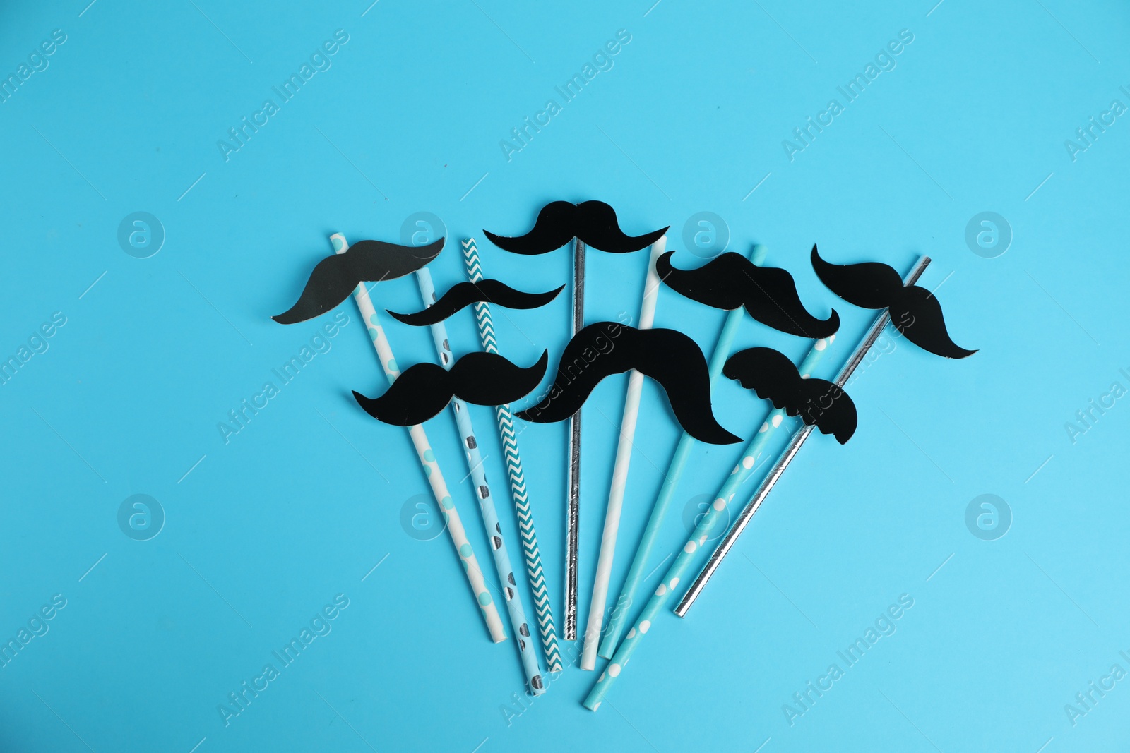 Photo of Fake paper mustaches with party props on light blue background, flat lay