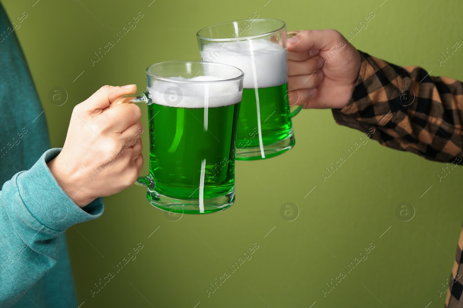 Photo of Man and woman toasting with green beer on color background, closeup. St. Patrick's Day celebration