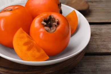 Photo of Delicious ripe persimmons on wooden table, closeup