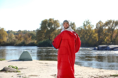 Photo of Male camper in sleeping bag on wild beach