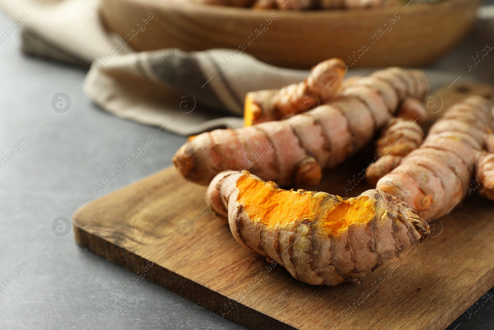 Photo of Many raw turmeric roots on grey table, closeup