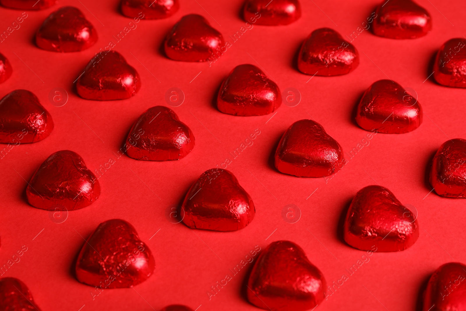 Photo of Tasty chocolate heart shaped candies on red background