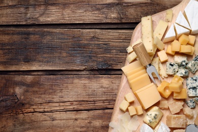 Cheese plate on wooden table, top view. Space for text