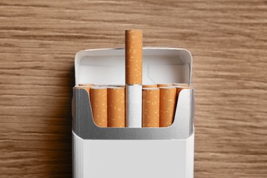 Cigarettes in pack on wooden table, top view