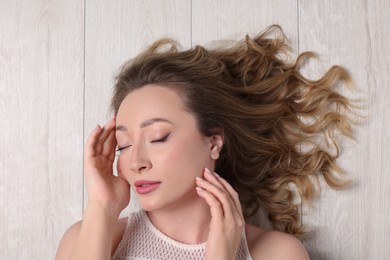 Photo of Portrait of beautiful woman with closed eyes on wooden floor, top view