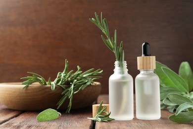 Photo of Bottles of essential oils and fresh herbs on wooden table, space for text