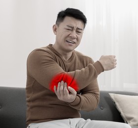 Image of Man suffering from rheumatism in elbow at home
