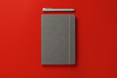 Gray notebook and pen on red background, flat lay