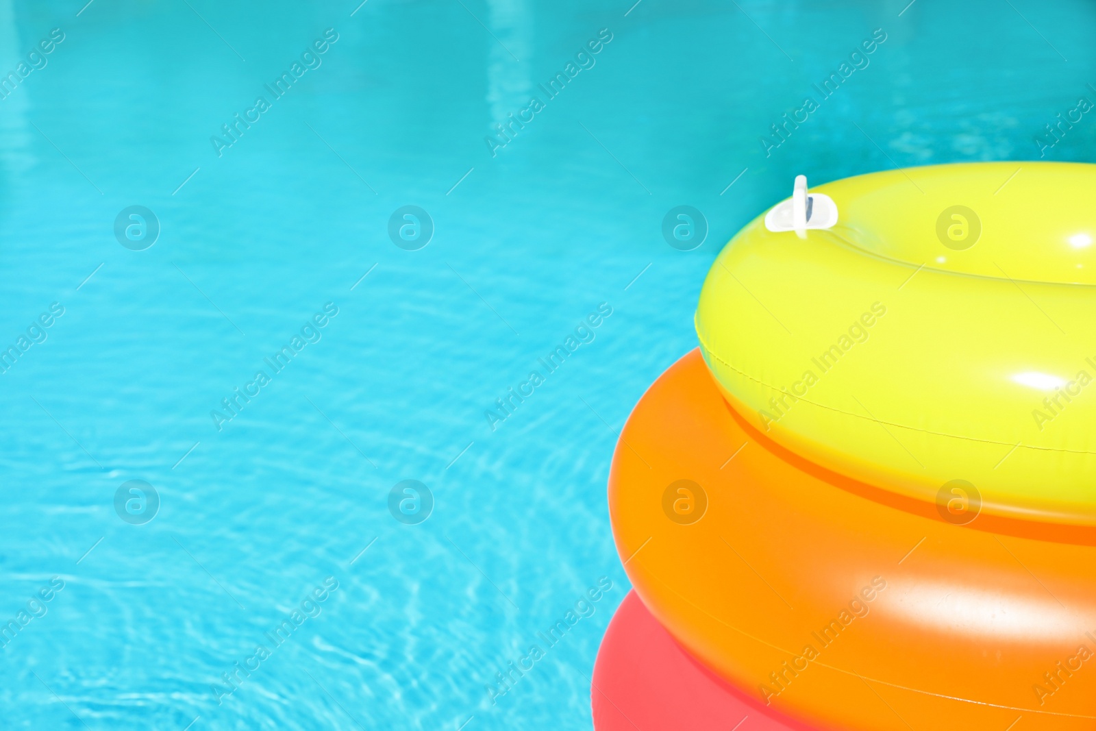 Photo of Modern swimming pool with inflatable rings outdoors. Space for text