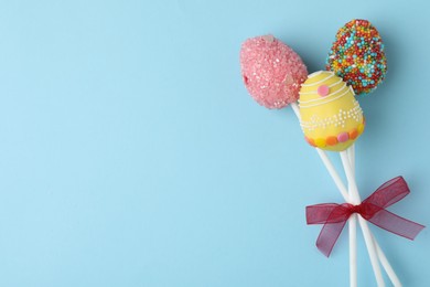 Photo of Egg shaped cake pops and space for text on light blue background, top view. Easter celebration