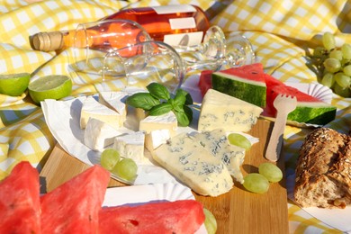 Photo of Delicious food and wine on picnic blanket, closeup