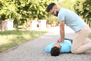 Passerby performing CPR on unconscious man in park. First aid
