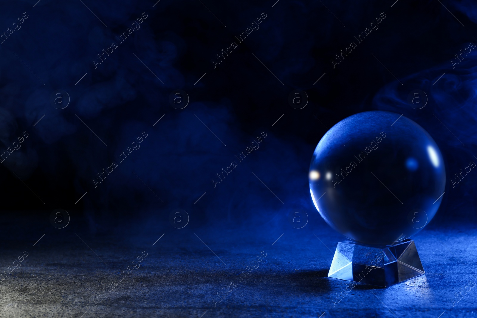 Photo of Magic crystal ball on table against dark background, space for text. Making predictions