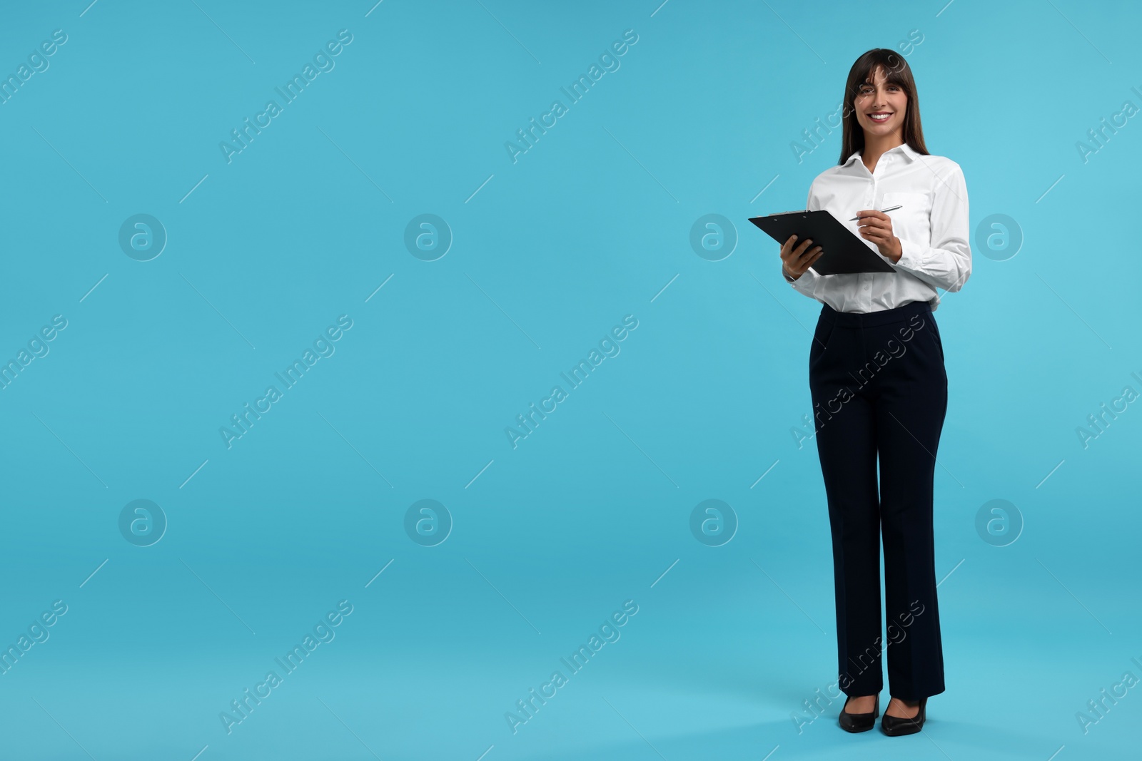 Photo of Happy secretary with clipboard and pen on light blue background. Space for text