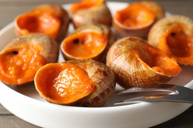 Photo of Delicious cooked snails with fork on table, closeup