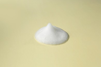 Foam on beige background. Face cleanser, skin care cosmetic