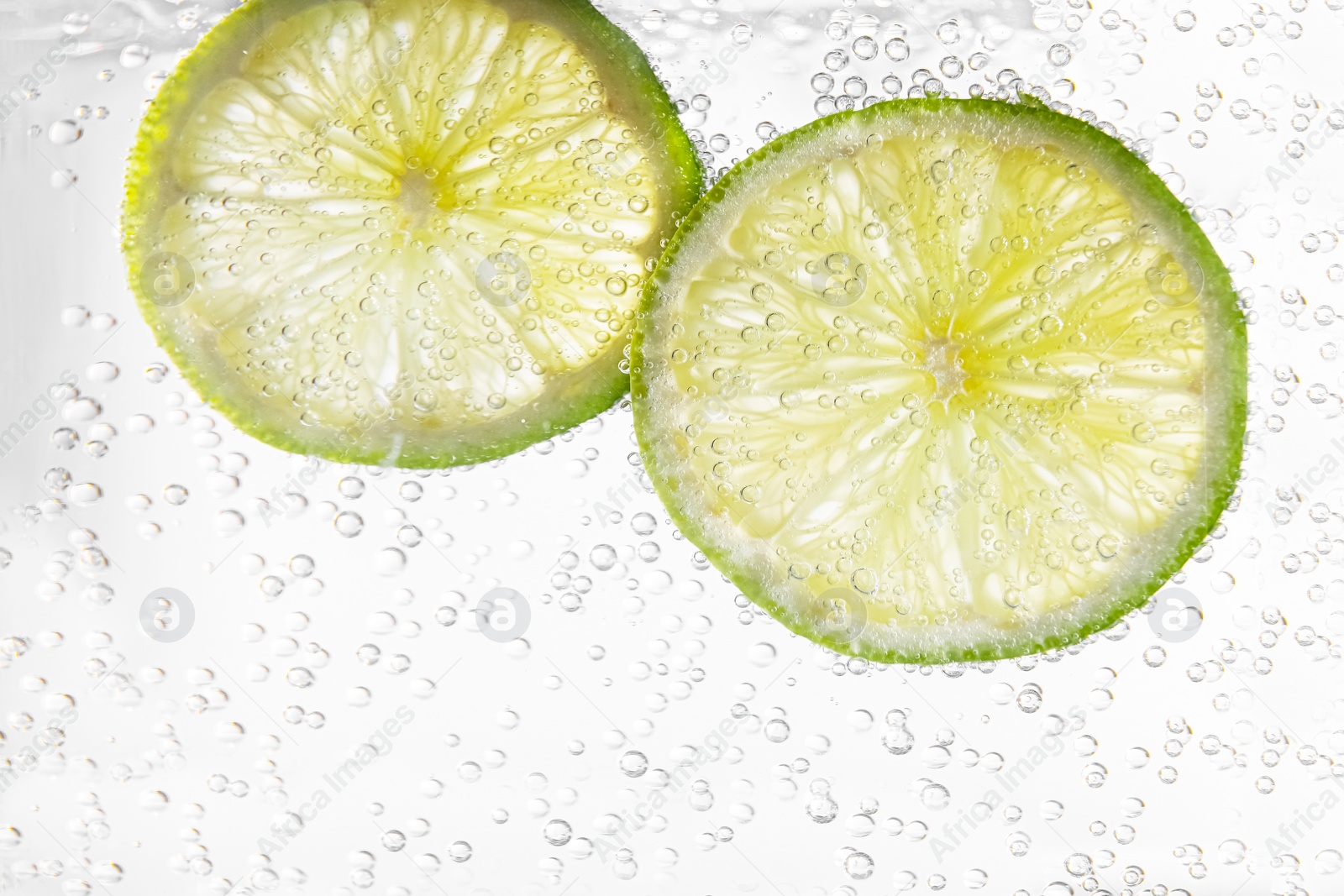 Photo of Juicy lime slices in soda water, closeup