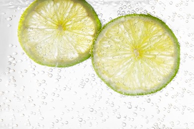 Photo of Juicy lime slices in soda water, closeup