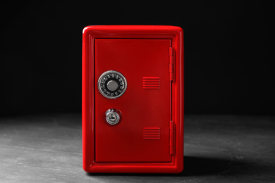 Photo of Red steel safe with mechanical combination lock against black background