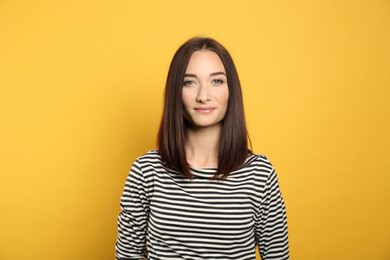 Portrait of pretty young woman with gorgeous chestnut hair on yellow background