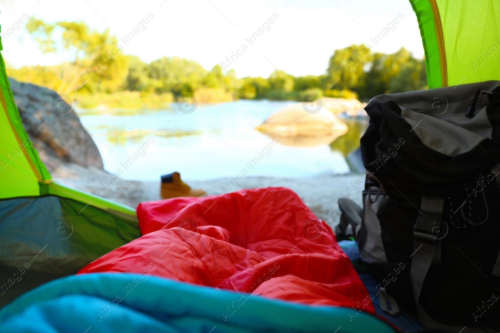 Photo of Camping tent with sleeping bag near lake, view from inside