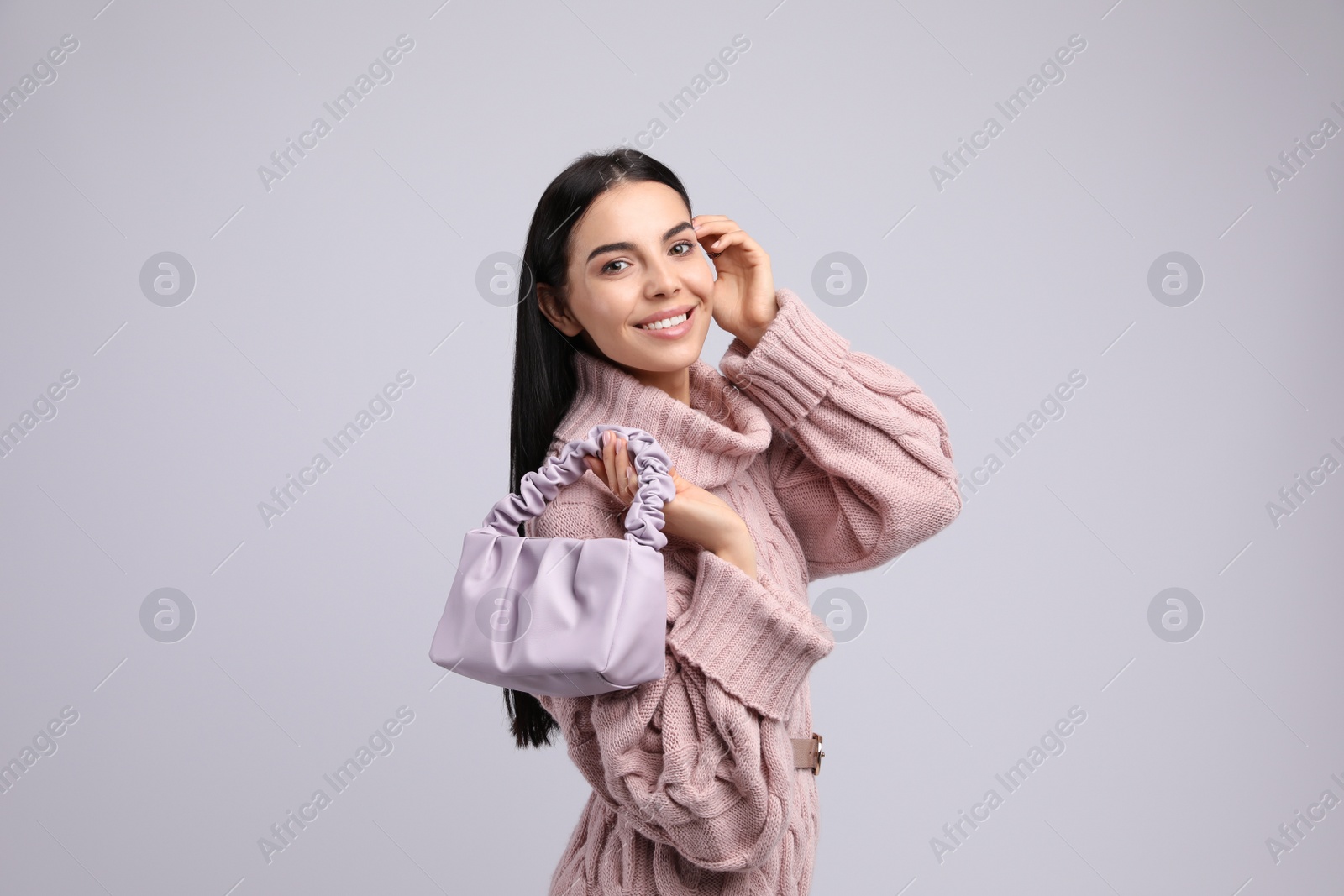 Photo of Fashionable young woman with stylish bag on light background