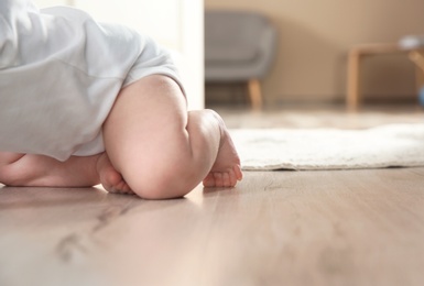 Photo of Cute little baby crawling on floor indoors, closeup with space for text