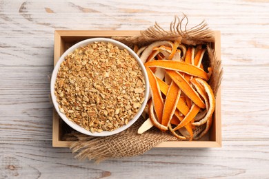 Photo of Dried orange seasoning zest and peel on white wooden table, top view