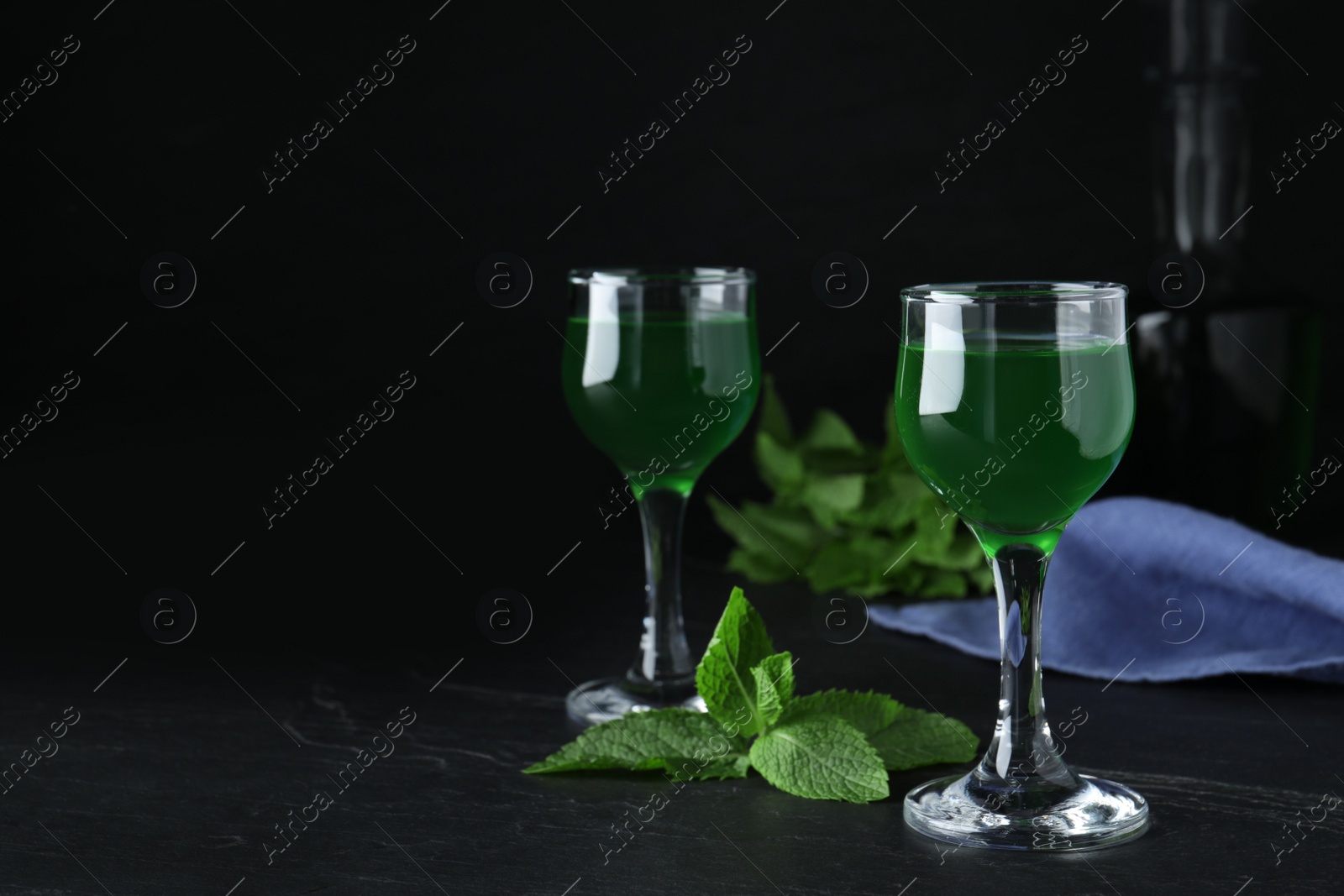 Photo of Delicious mint liqueur on black table. Space for text