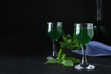 Photo of Delicious mint liqueur on black table. Space for text