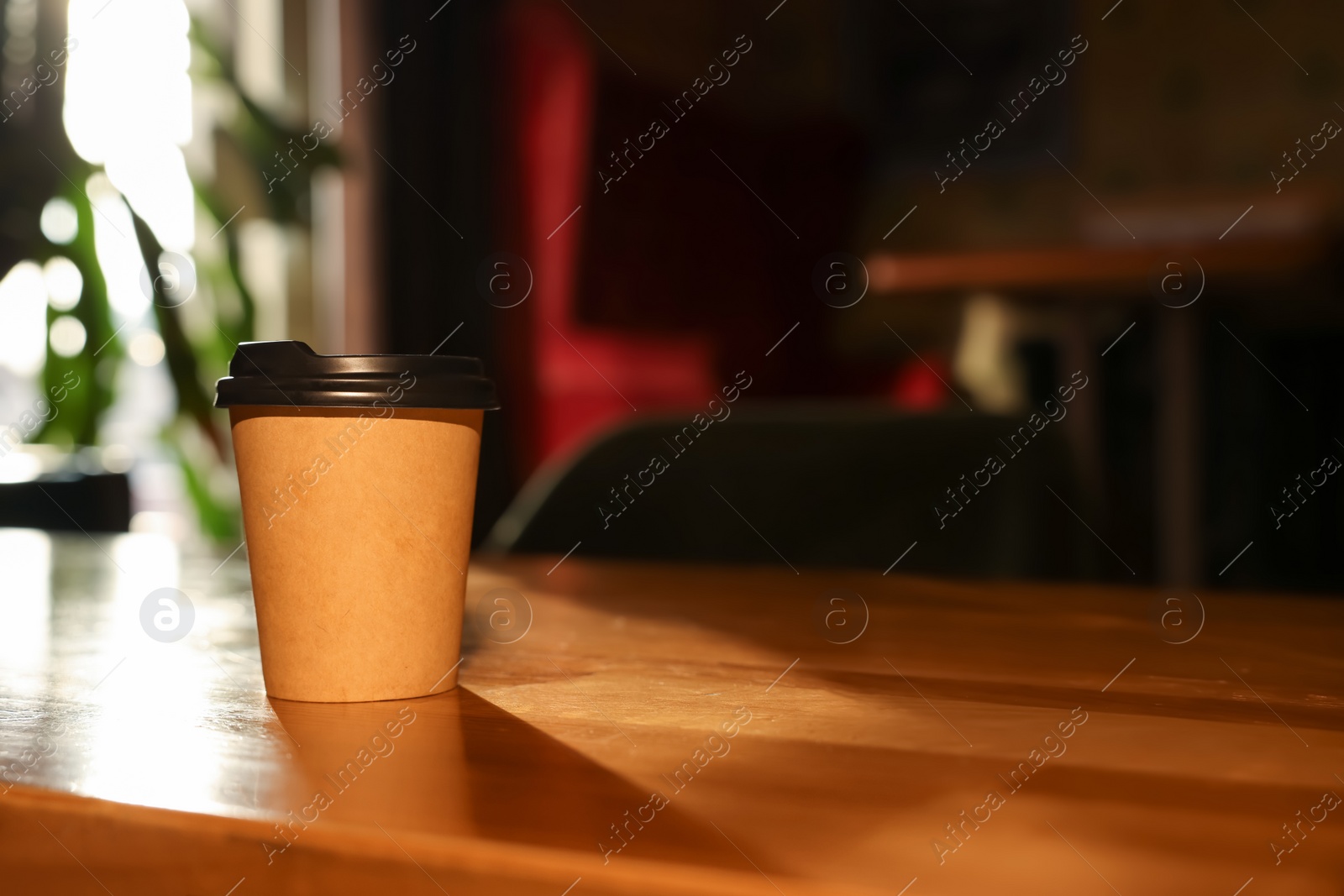 Photo of Paper coffee cup on wooden table in cafe. Space for text