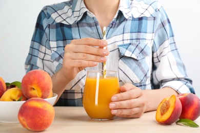 Photo of Woman with natural peach juice at wooden table, closeup