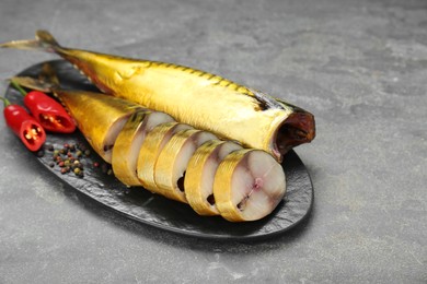 Photo of Delicious smoked mackerels with pepper, dill and spices on dark grey table