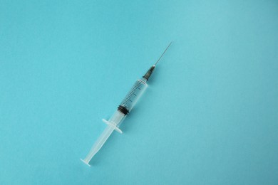 Photo of Medical syringe on light blue background, top view