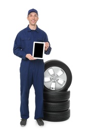 Young auto mechanic holding tablet PC on white background