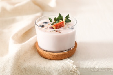 Photo of Delicious fig smoothie in glass on white wooden table