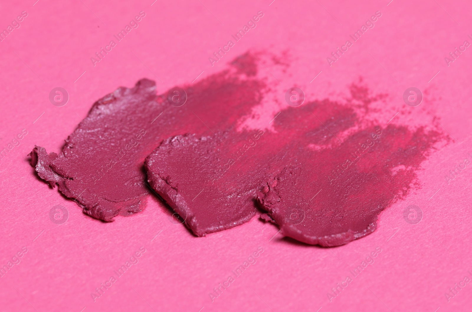 Photo of Smears of bright lipstick on pink background, closeup