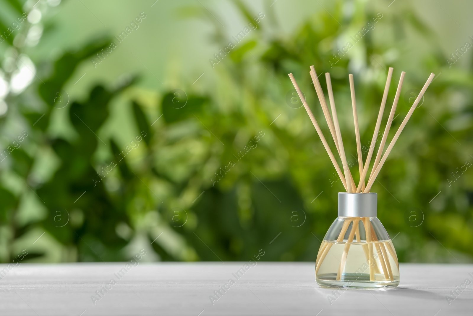 Photo of Aromatic reed freshener on table against blurred background