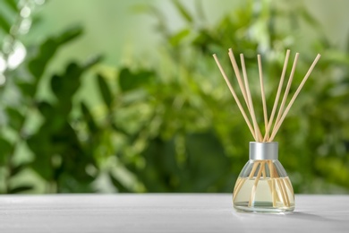 Photo of Aromatic reed freshener on table against blurred background